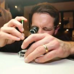 HEDGE writer Jon Hawkins examining and dismantling a watch closely with a magnifying eye piece.